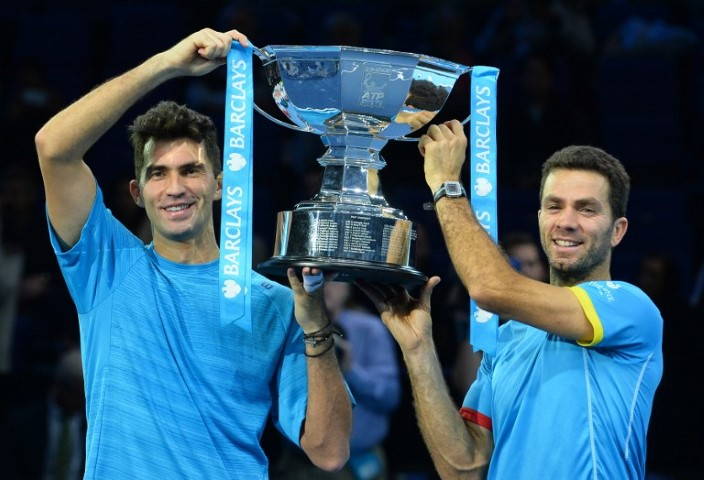 Netherland's Jean-Julien Rojer (R) and Romania's Horia Tecau hold up the trophy after winning the men's doubles final match against India's Rohan Bopanna and Romania's Florin Mergea on day eight of the ATP World Tour Finals tennis tournament in London on November 22, 2015.  AFP PHOTO / GLYN KIRK / AFP / GLYN KIRK